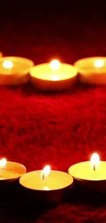 Heart-shaped candles glowing on a red background.