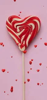 Heart-shaped red and white lollipop on pink background.