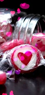 Pink heart candies spilling from a jar on black background.