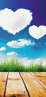 Wallpaper with heart-shaped clouds in a blue sky over grass and wood deck.