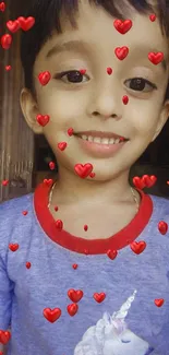 Smiling child with heart emojis on blue shirt wallpaper.