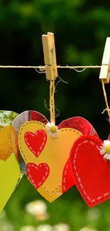 Heart-shaped crafts on a line with wooden clothespins on a lush green backdrop.