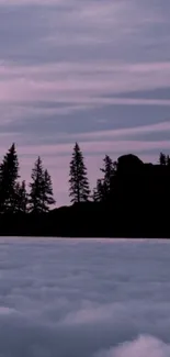 Silhouette of a person making a heart shape during a purple mountain sunset.