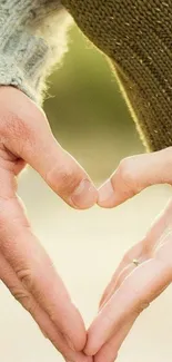 Heart-shaped hands in warm tones, romantic mobile background.