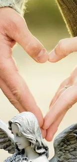 Hands form a heart around an angel statue, symbolizing love and peace.