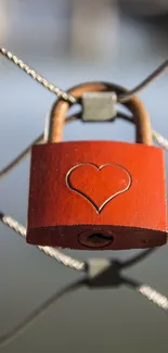 Red heart-engraved lock on wire fence, symbolizing love and security.