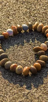 A heart made of beach stones on sunlit sand.