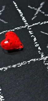 Red heart on black chalkboard with tic-tac-toe design.