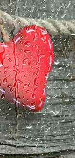 Red heart hanging on wood with raindrops