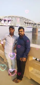 Two men stand by a bridge with heart overlays, creating a picturesque scene.