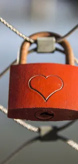 Red padlock with heart on metal fence symbolizing love.