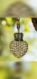 Heart-shaped pendant with sparkling stones hanging in front of a blurred nature background.