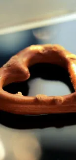 Heart-shaped pretzel resting on a smartphone surface.