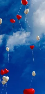 Red and white heart balloons in a blue sky