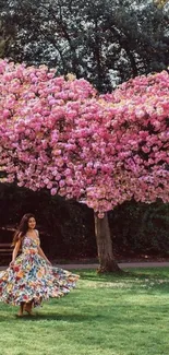 A woman twirls under a heart-shaped pink blossom tree in a park.