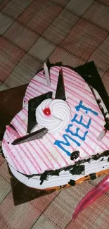 Heart-shaped cake with decorations on a plaid tablecloth.