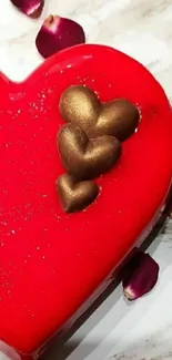 Heart-shaped red cake with golden hearts and rose petals on a plate.