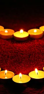 Heart-shaped candle arrangement glowing warmly on red background.