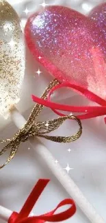 Heart-shaped glittery candy lollipops with bows on a plate.