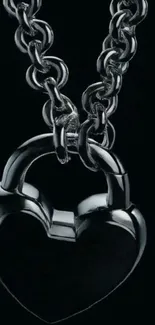 Heart-shaped metal lock with chain on black background.