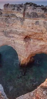 Heart-shaped coastal rock arch at sunset over ocean.