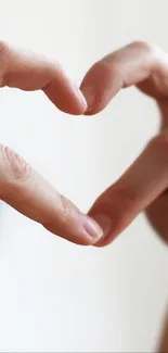 Hands forming a heart-shaped gesture on a light background.