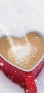 Heart-shaped red mug filled with coffee in the snow.