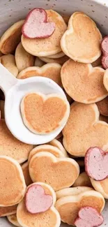 Heart-shaped pancakes in a bowl, perfect for a cute phone wallpaper backdrop.