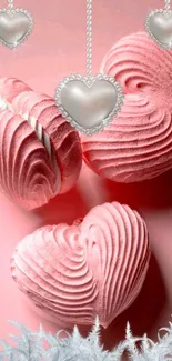 Heart-shaped pink desserts with dangling chains on a mobile wallpaper.