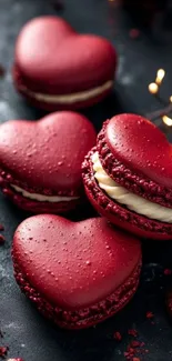 Heart-shaped red macarons on a dark background.