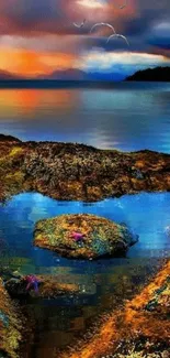 Sunset over a heart-shaped rocky shoreline with blue waters.