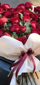 Heart-shaped bouquet of red roses with a large white bow.