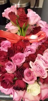 Heart-shaped bouquet of red and pink roses on a surface.