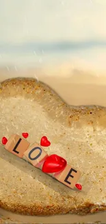 Heart-shaped sand with love scrabble tiles and red hearts on a beach.