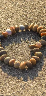 Pebble heart shape on sandy beach background.