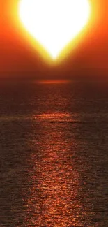 Heart-shaped sunset casting orange glow on ocean.