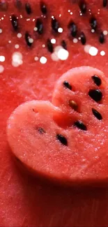 Heart-shaped watermelon slice with seeds on red background.