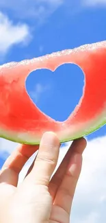 Heart-shaped watermelon slice against a sunny blue sky, creating a vibrant scene.