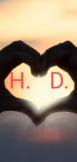 Silhouette of hands forming a heart against a sunset.