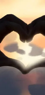 Silhouette of hands forming a heart against a vibrant orange sunset.