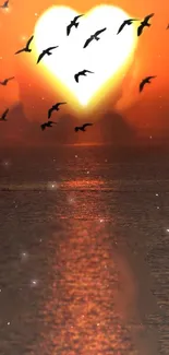 Heart-shaped sunset with birds over ocean.