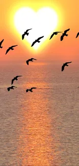 Heart-shaped sunset with birds over the ocean.