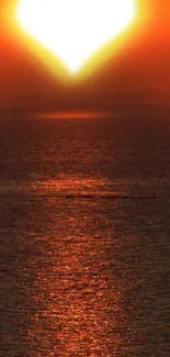 Heart-shaped sunset over ocean with vibrant orange hues.