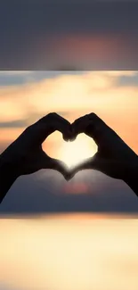 Silhouette of hands forming a heart against a vibrant sunset sky.