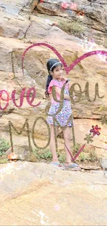 Child standing on rocks with heart-shaped 'Love You Mom' text.