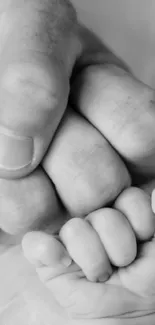 Black and white image of baby and adult hands touching, symbolizing connection.