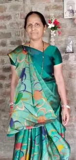 A woman in teal green saree with 'I miss u mummy' text on brick wall background.