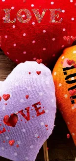 Three heart-shaped cushions with love text, in red, purple, and orange colors.