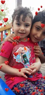 Children embracing in a playground with heart decorations.