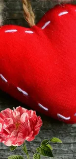 Red fabric heart with flower design on wood background.